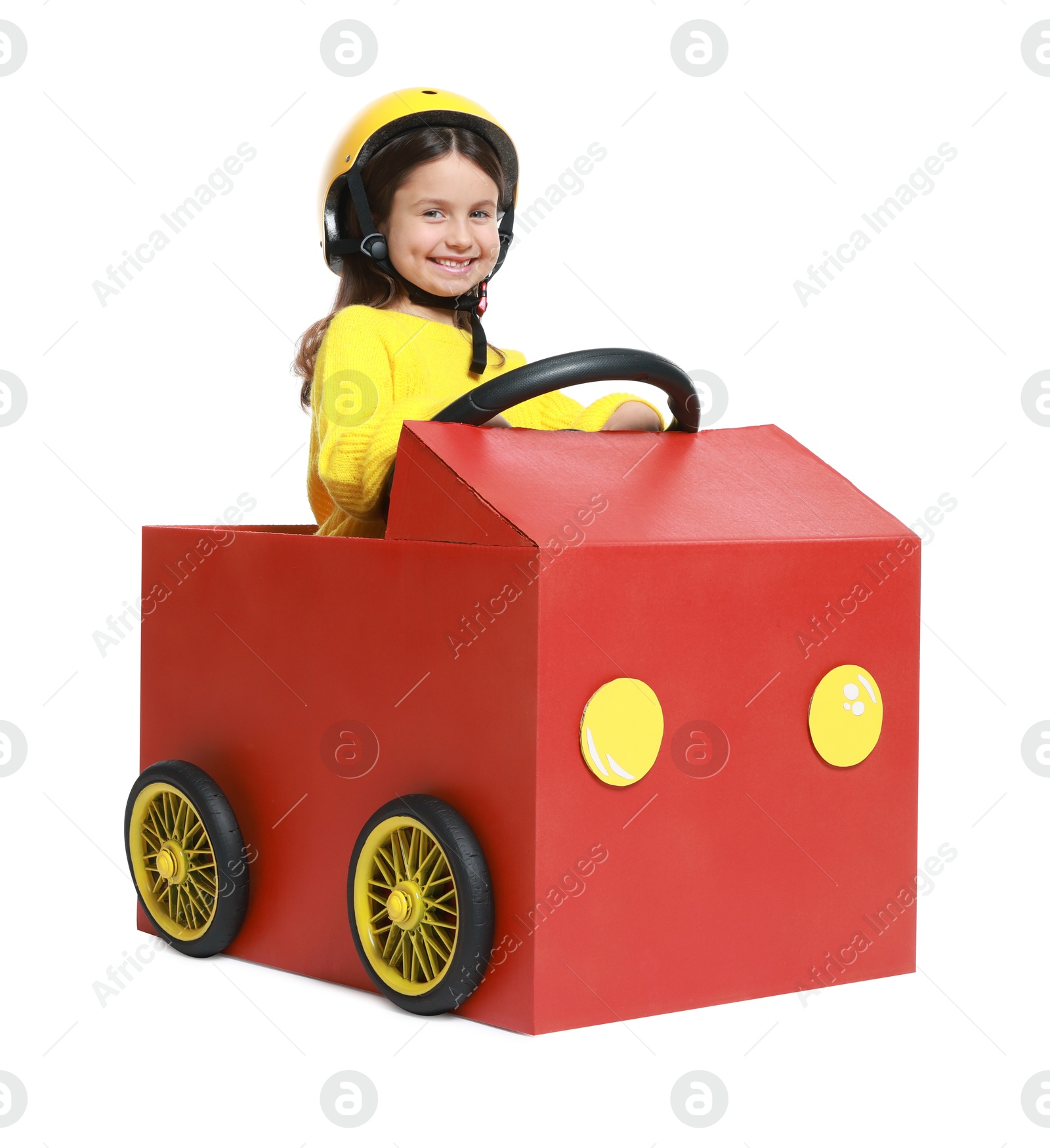 Photo of Little girl driving car made with cardboard on white background