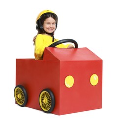 Photo of Little girl driving car made with cardboard on white background