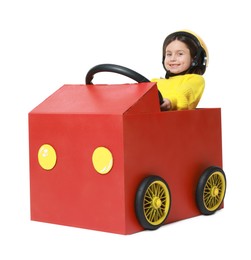 Photo of Little girl driving car made with cardboard on white background