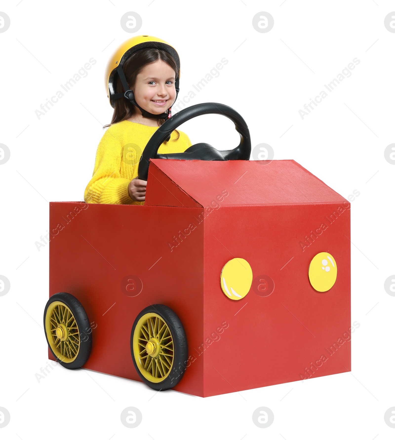 Photo of Little girl driving car made with cardboard on white background