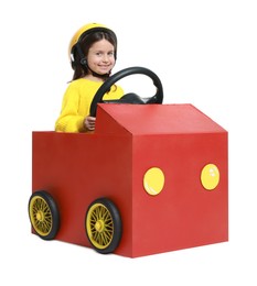 Little girl driving car made with cardboard on white background