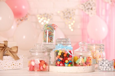 Photo of Candy bar. Many different sweets and gift boxes on white wooden table in festive decorated room