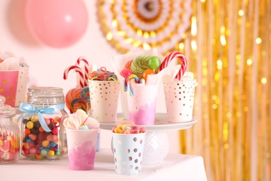 Photo of Candy bar. Many different sweets on table in festive decorated room, space for text