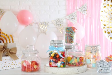 Photo of Candy bar. Many different sweets on white wooden table in festive decorated room