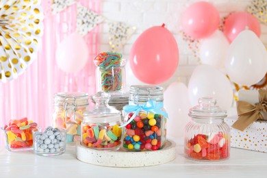 Photo of Candy bar. Many different sweets on white wooden table in festive decorated room