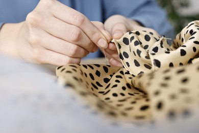 Photo of Woman sewing fabric with needle and thread at indoors, closeup