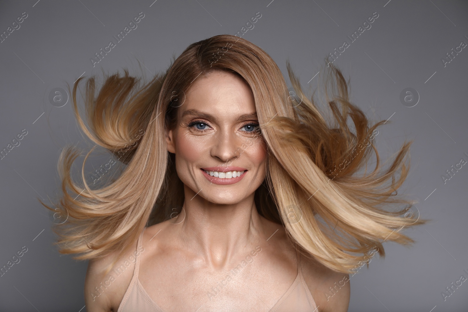 Photo of Portrait of beautiful happy woman with blonde hair on grey background