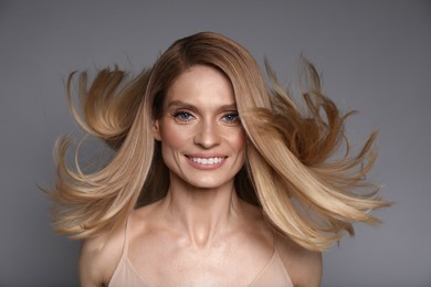 Photo of Portrait of beautiful happy woman with blonde hair on grey background