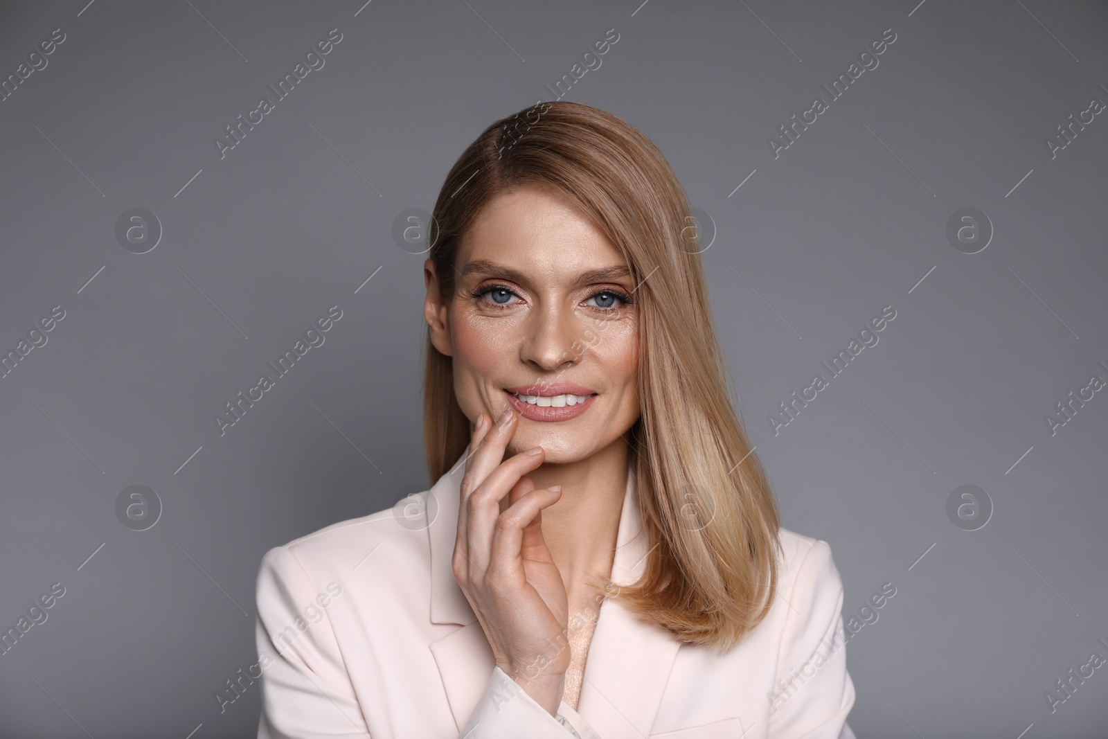 Photo of Portrait of beautiful happy woman with straight blonde hair on grey background