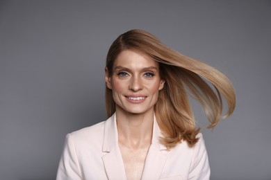 Photo of Portrait of beautiful happy woman with straight blonde hair on grey background