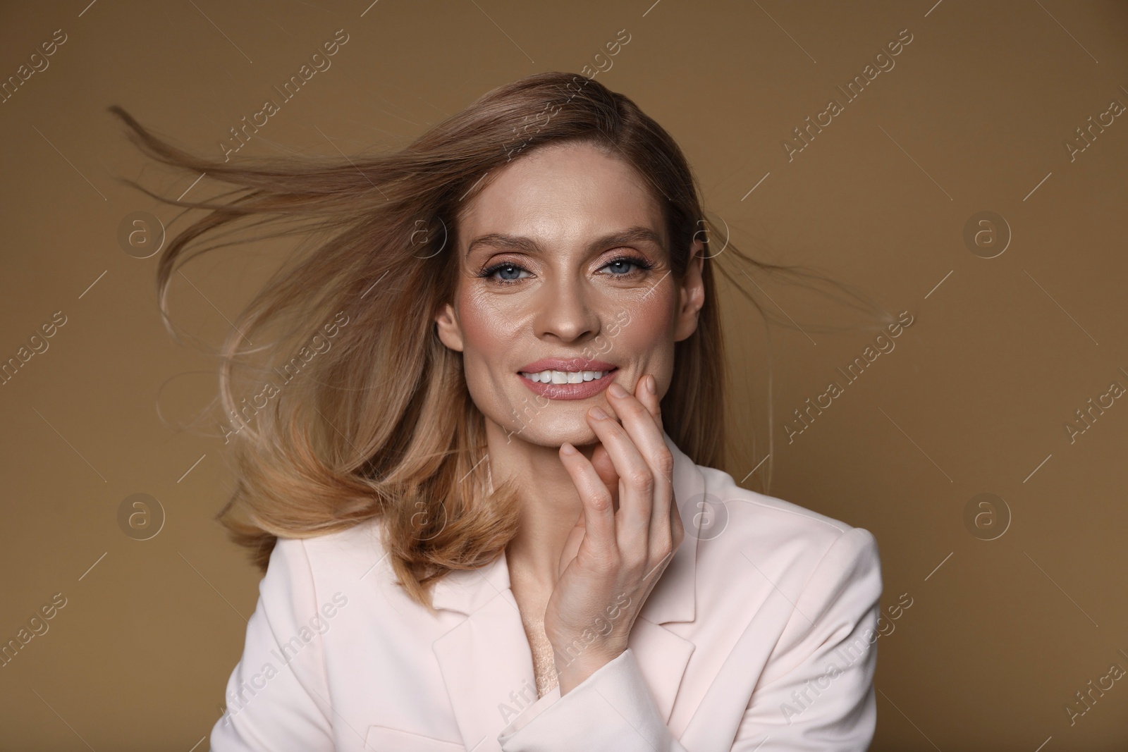 Photo of Portrait of beautiful happy woman with straight blonde hair on light brown background