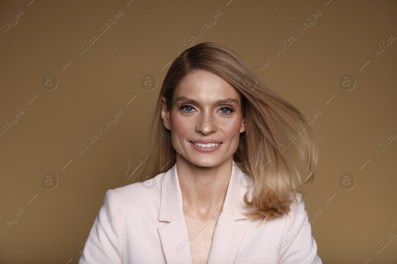 Photo of Portrait of beautiful happy woman with straight blonde hair on light brown background