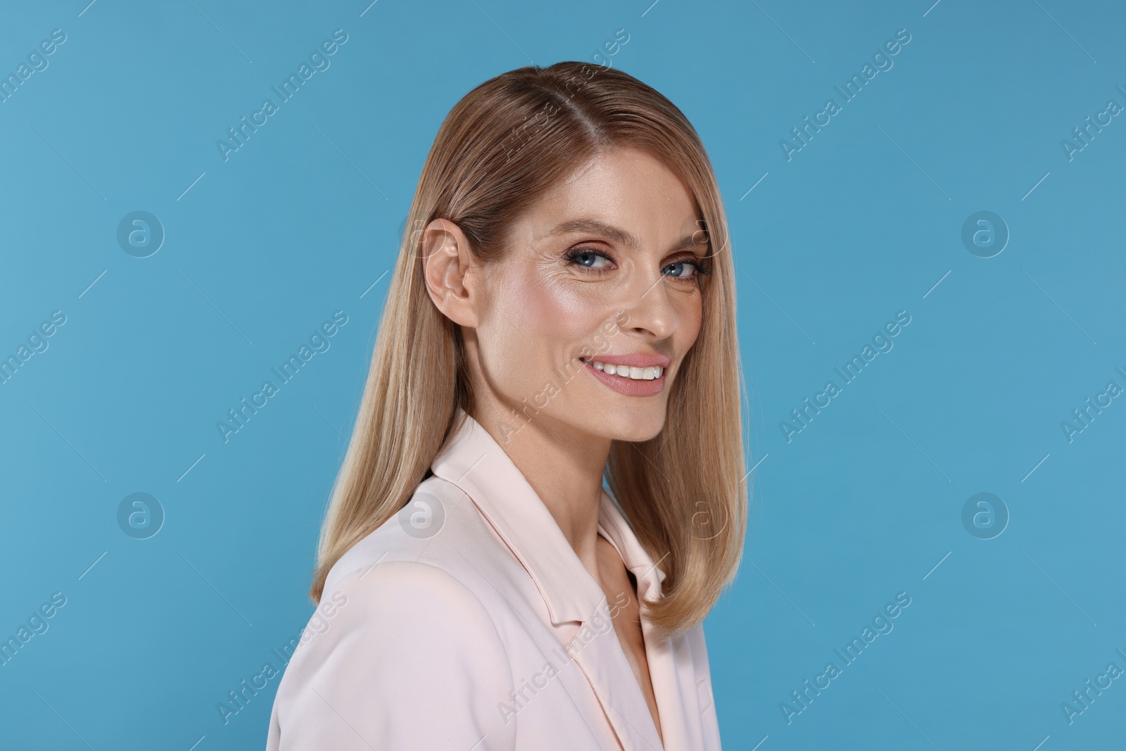 Photo of Portrait of beautiful happy woman with straight blonde hair on light blue background