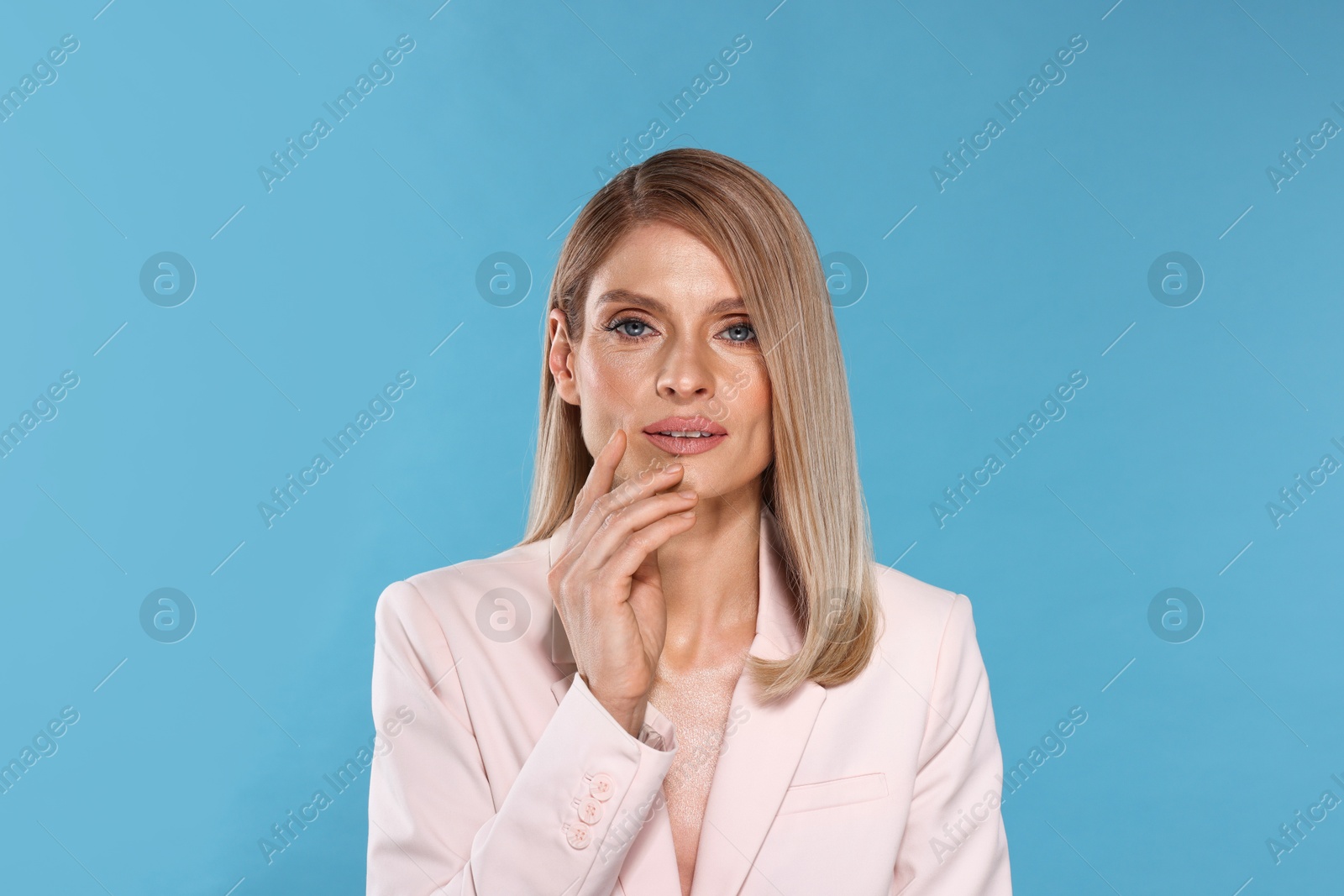 Photo of Portrait of beautiful woman with straight blonde hair on light blue background