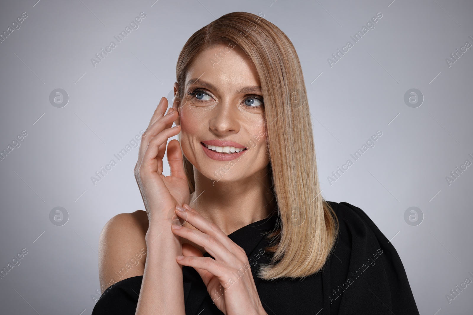 Photo of Portrait of beautiful happy woman with straight blonde hair on grey background