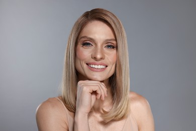 Photo of Portrait of beautiful happy woman with straight blonde hair on grey background