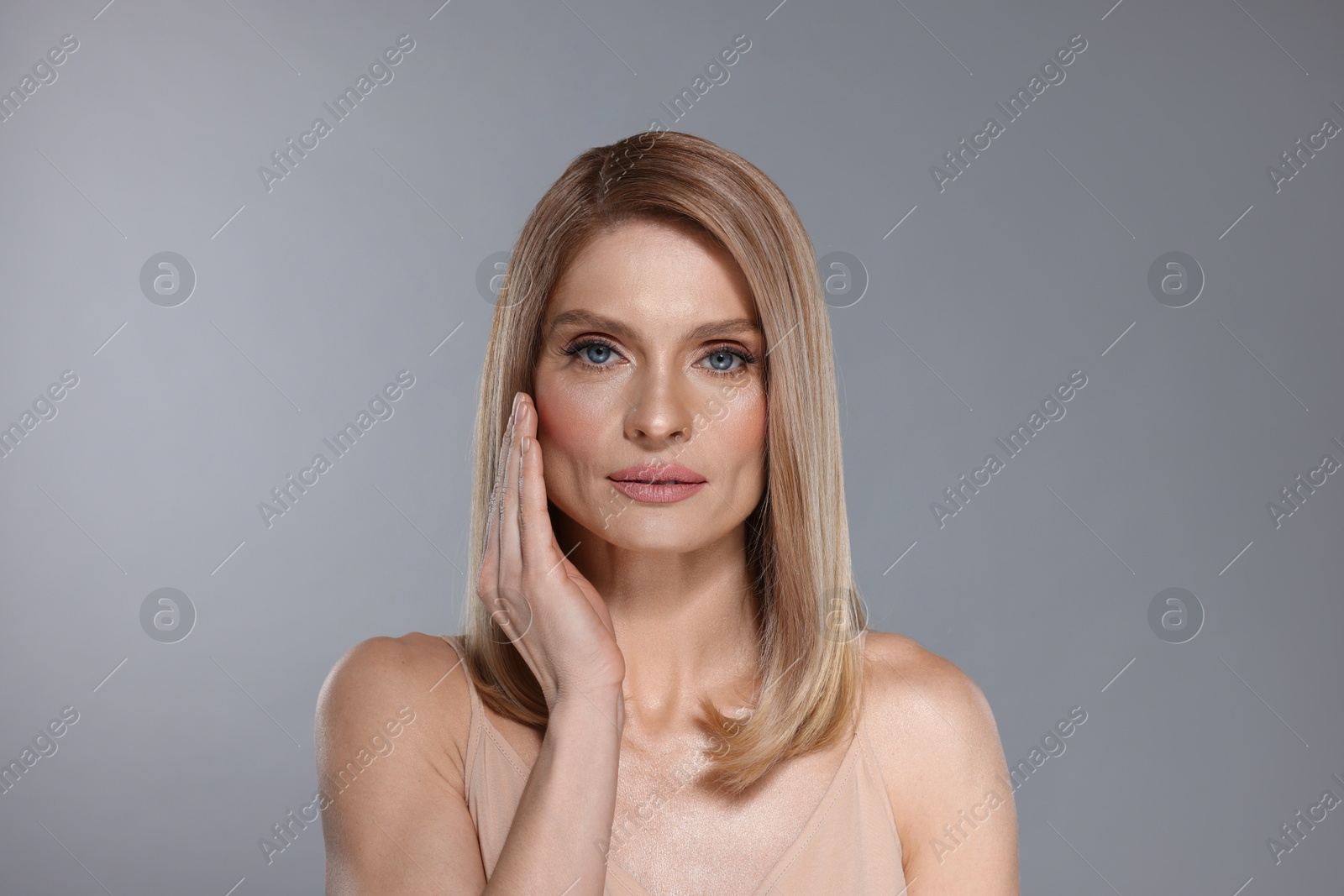 Photo of Portrait of beautiful woman with straight blonde hair on grey background