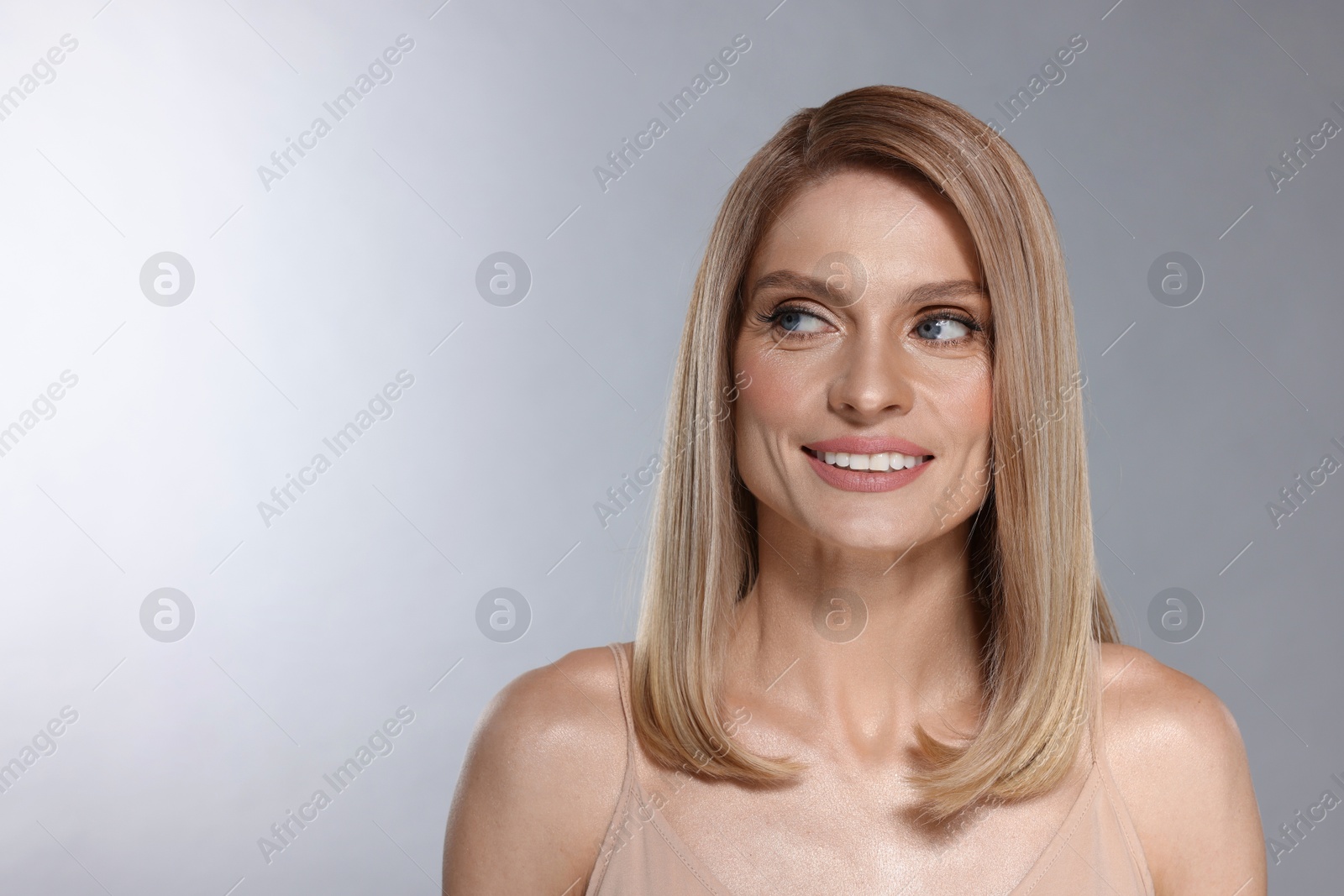 Photo of Portrait of beautiful happy woman with straight blonde hair on light grey background, space for text