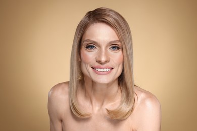 Photo of Portrait of beautiful happy woman with straight blonde hair on beige background