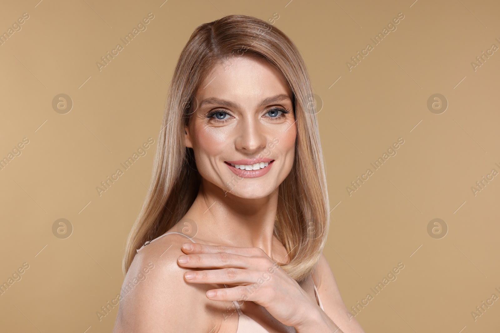 Photo of Portrait of beautiful happy woman with straight blonde hair on beige background