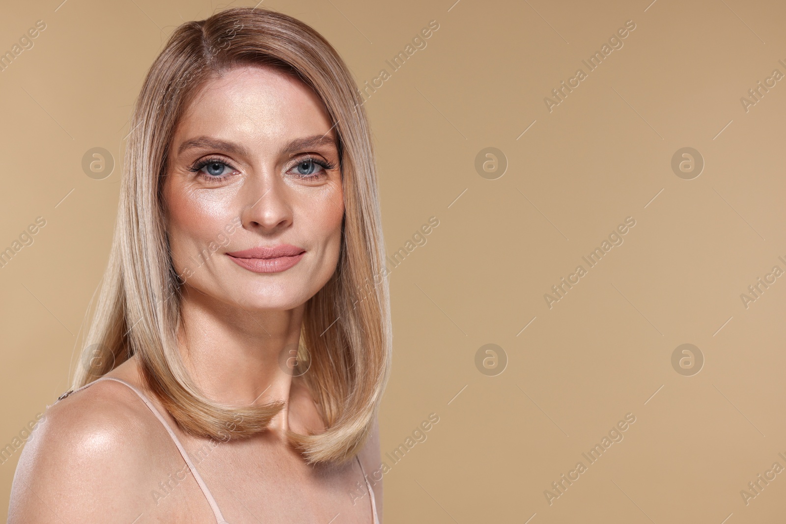 Photo of Portrait of beautiful woman with straight blonde hair on beige background, space for text