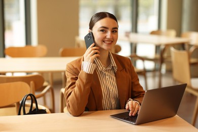 Photo of Woman in stylish formal suit working at table indoors