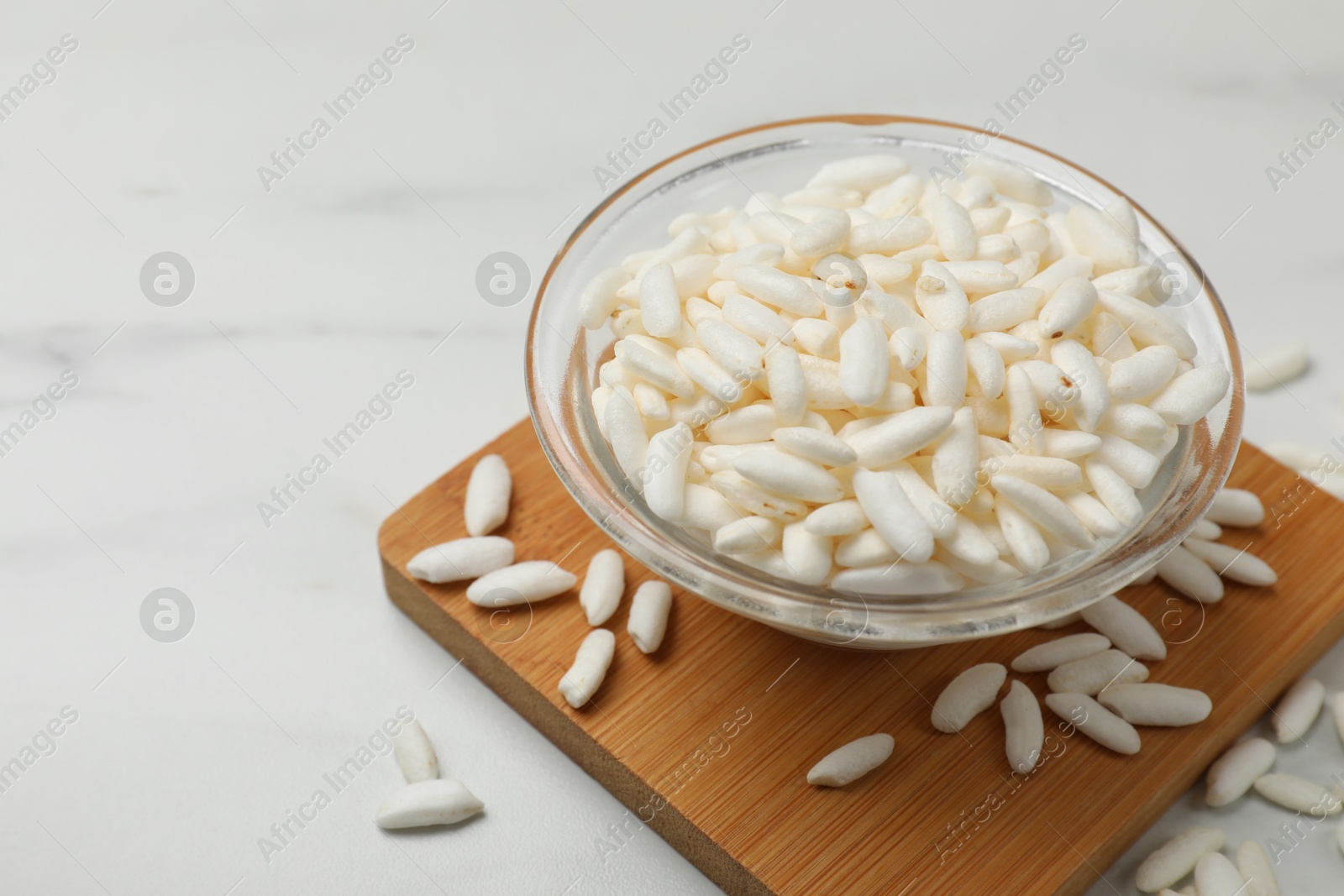 Photo of Puffed rice in bowl on white table, closeup