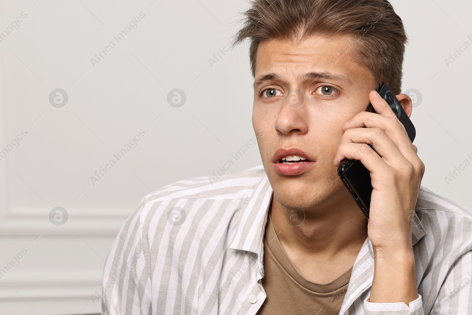 Photo of Worried man calling hotline for mental health help at home. Space for text