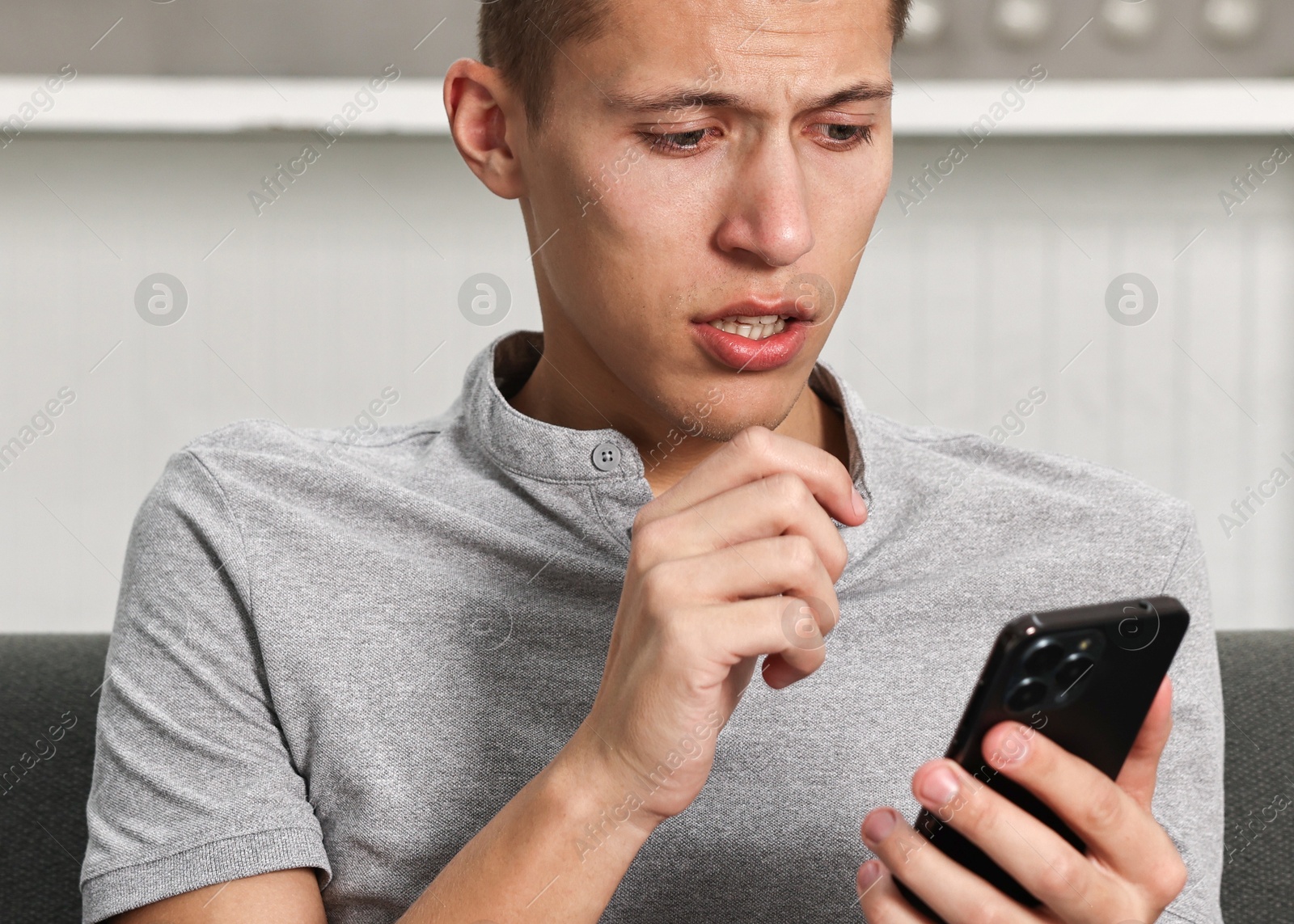 Photo of Stressed man calling hotline for mental health help on sofa in kitchen