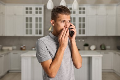 Photo of Worried man calling hotline for mental health help in kitchen