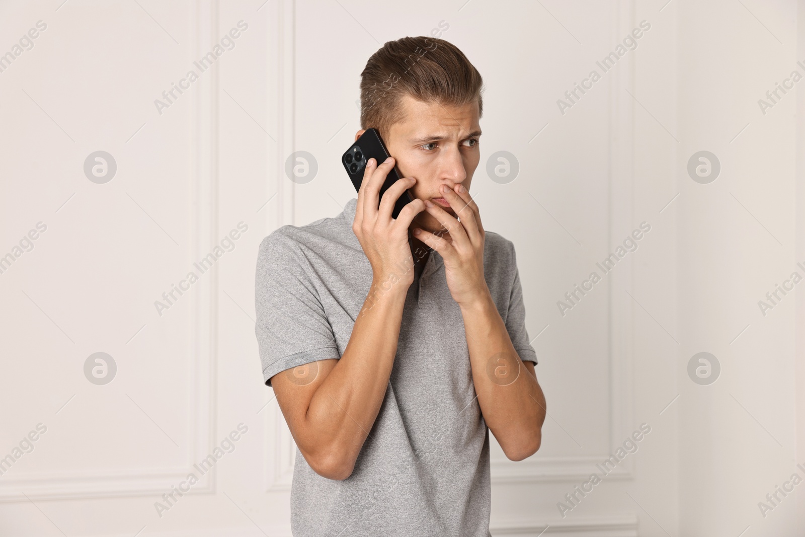 Photo of Stressed man calling hotline for mental health help indoors