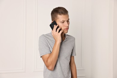 Photo of Frustrated man calling hotline for mental health help indoors