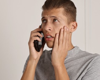 Photo of Stressed man calling hotline for mental health help indoors