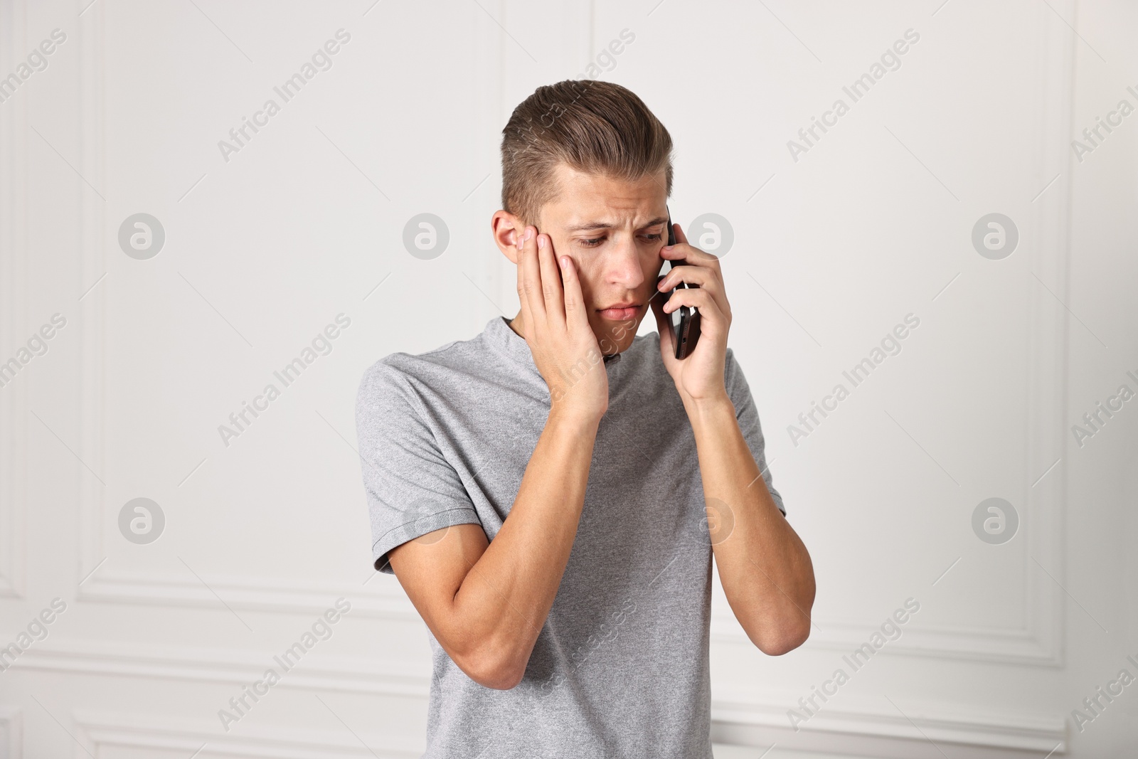 Photo of Stressed man calling hotline for mental health help indoors