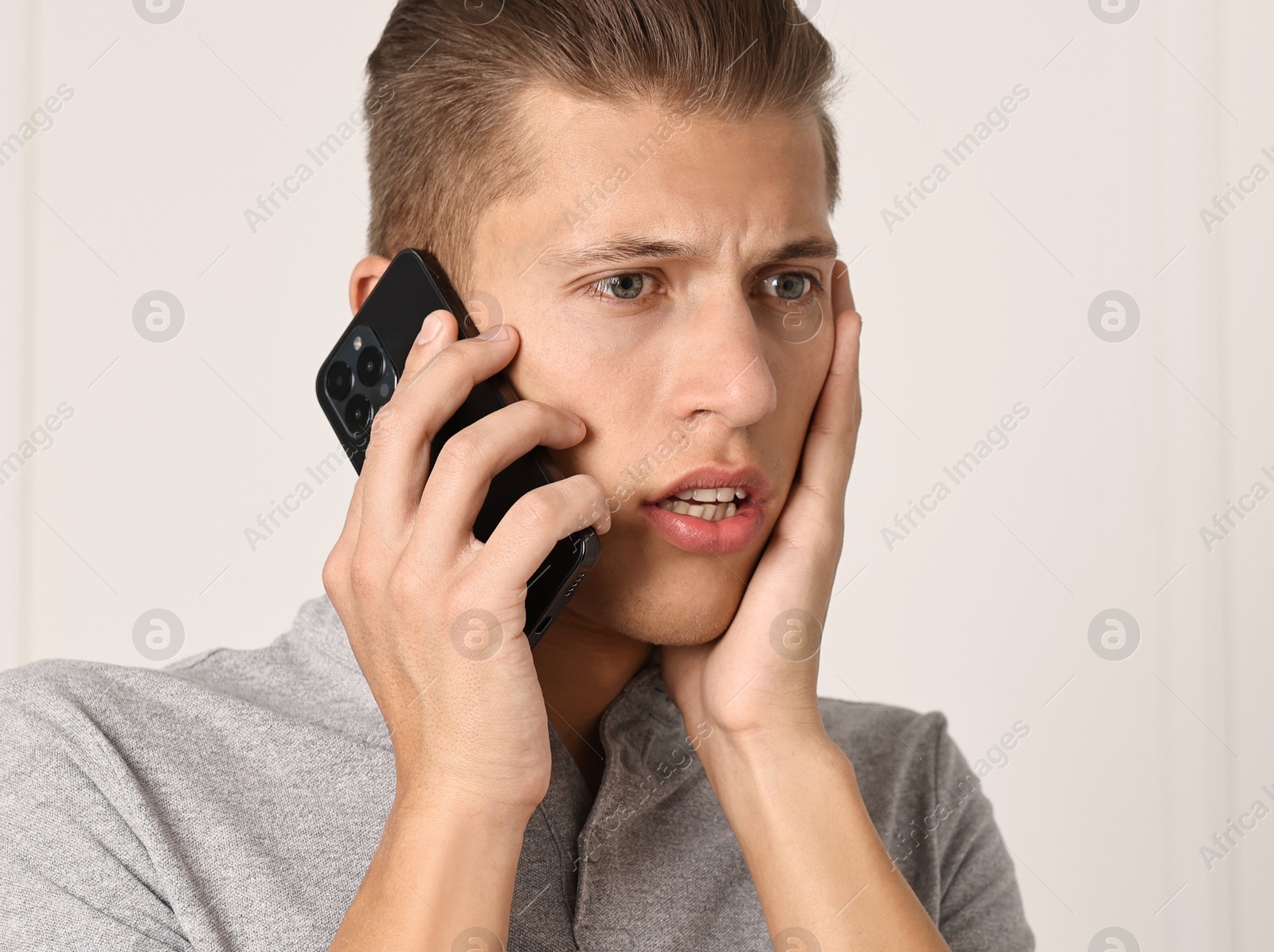 Photo of Stressed man calling hotline for mental health help indoors