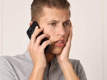 Photo of Stressed man calling hotline for mental health help indoors