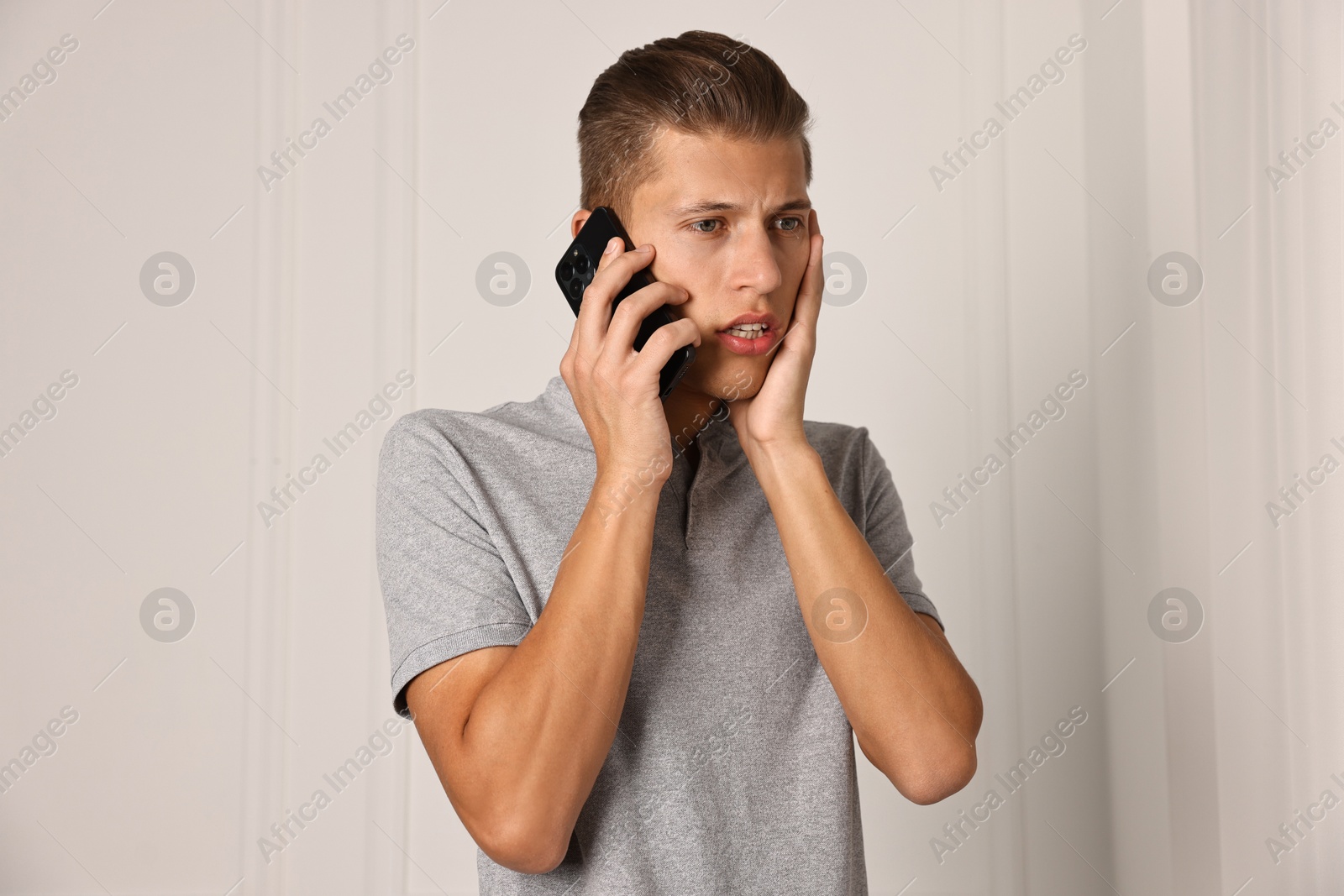 Photo of Stressed man calling hotline for mental health help indoors