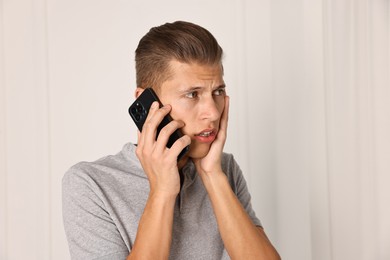 Photo of Stressed man calling hotline for mental health help indoors