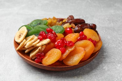 Photo of Mix of different dried fruits in bowl on light grey table, closeup