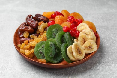 Photo of Mix of different dried fruits in bowl on light grey table, closeup