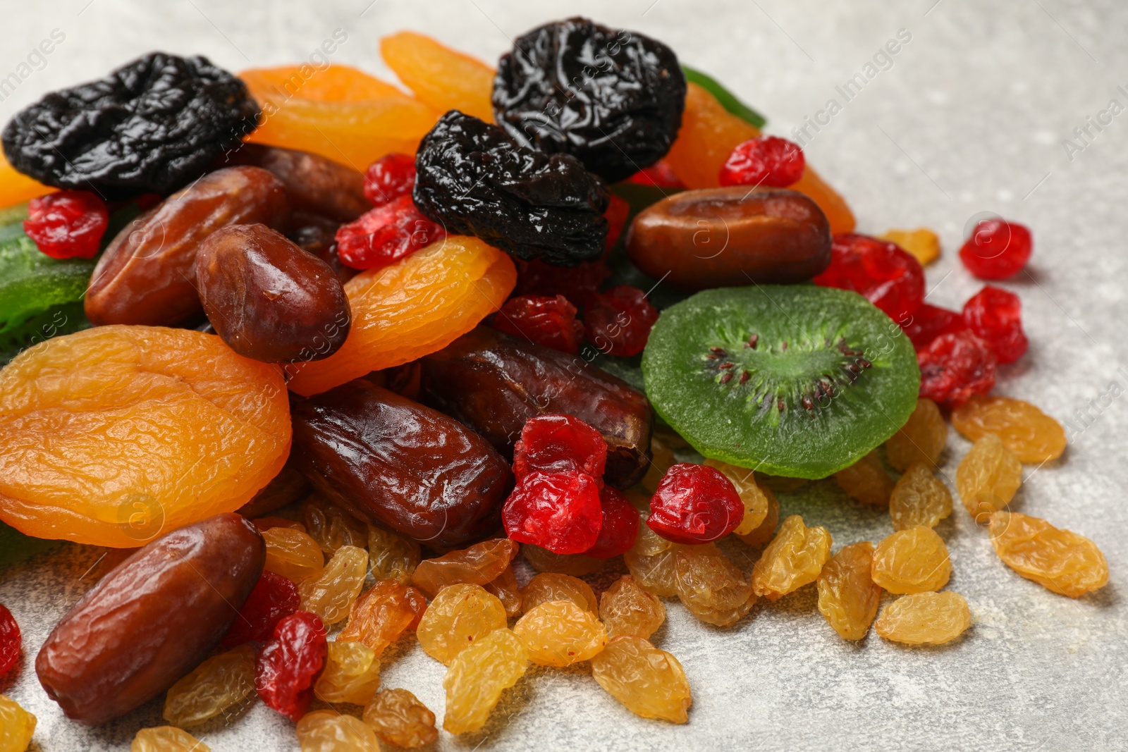 Photo of Mix of different dried fruits on light grey table, closeup