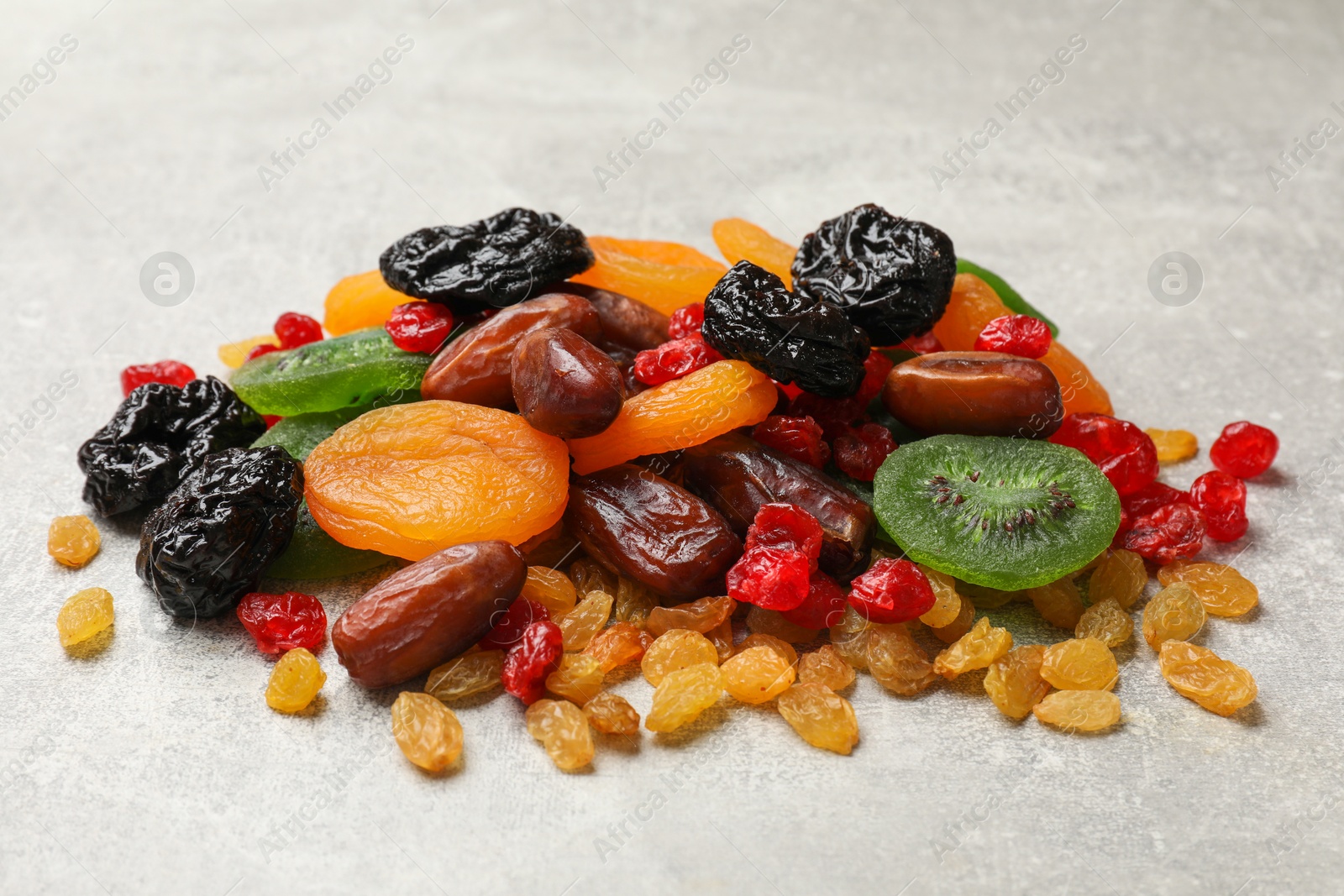 Photo of Mix of different dried fruits on light grey table, closeup