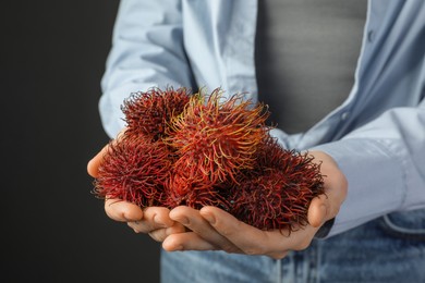 Photo of Woman holding fresh rambutans against black background, closeup