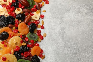 Photo of Mix of different dried fruits on gray textured table, top view. Space for text