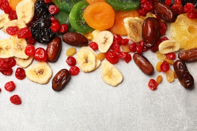 Photo of Mix of different dried fruits on gray textured table, top view. Space for text