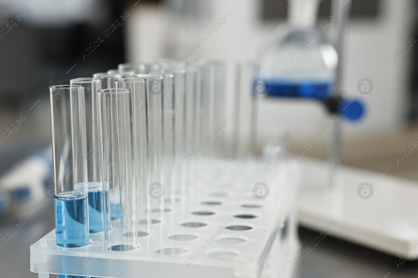 Photo of Test tubes with blue liquid on table in laboratory, closeup. Space for text