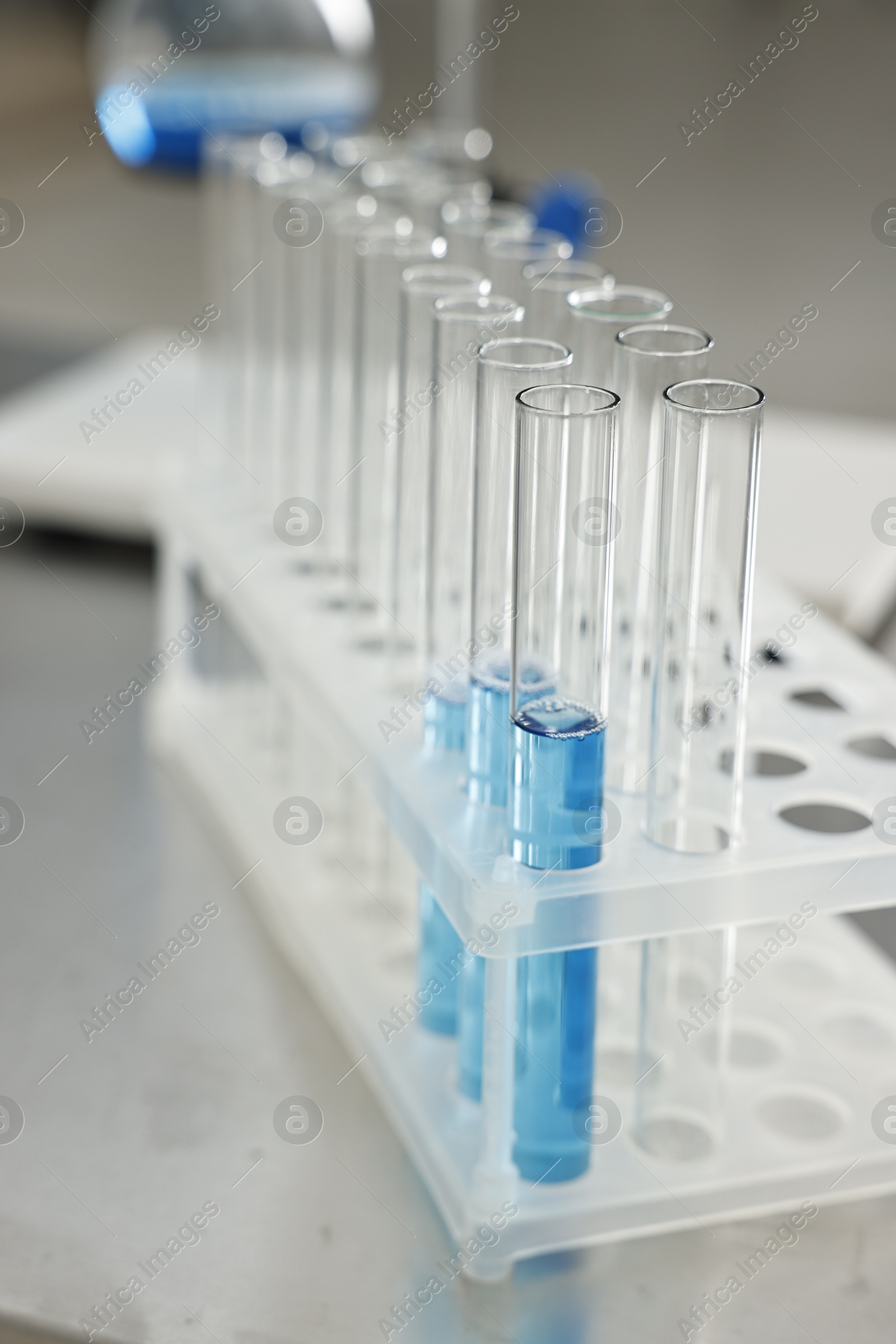 Photo of Test tubes with blue liquid on table in laboratory, closeup