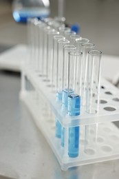 Photo of Test tubes with blue liquid on table in laboratory, closeup