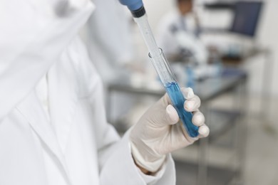 Photo of Scientist with micropipette and test tube working in laboratory, closeup