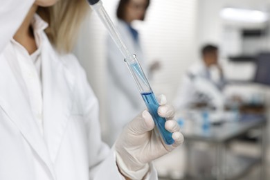 Photo of Scientist with micropipette and test tube working in laboratory, closeup